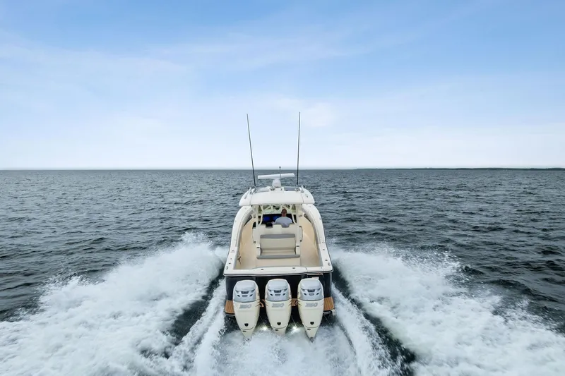 Slide: The Image of 2020 Scout 355 LXF boat cruising on open water, rear view. - 12