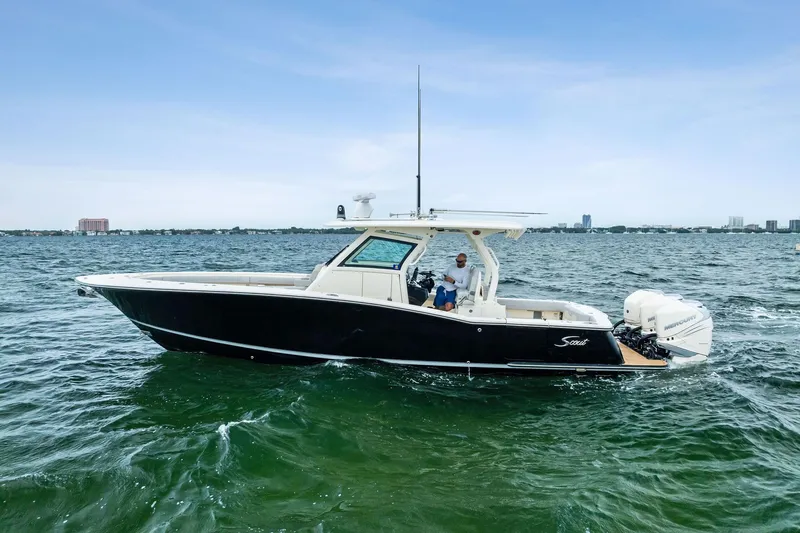 Slide: The Image of 2020 Scout 355 LXF boat cruising on open water under clear skies. - 2