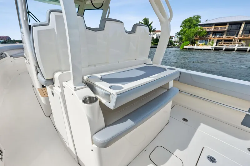 Slide: The Image of 2020 Scout 355 LXF boat interior with seating and cup holders on a sunny day. - 29
