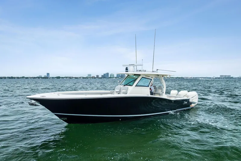 Slide: The Image of 2020 Scout 355 LXF boat on open water, sleek design, city skyline in background. - 4