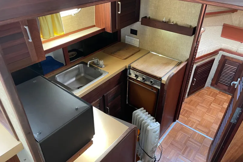 Slide: The Image of 1982 Mainship 34 MK 1 galley with wood cabinetry, sink, stove, and parquet flooring. - 17