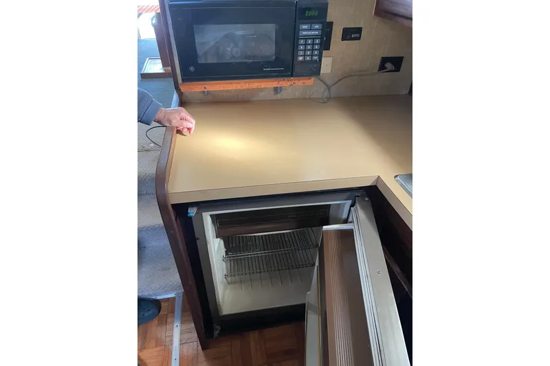 Slide: The Image of 1982 Mainship 34 MK 1 galley with microwave and open fridge. - 24