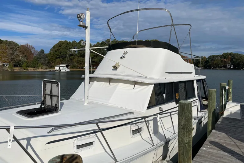 Slide: The Image of 1982 Mainship 34 MK 1 docked by a serene lake with trees in the background. - 4
