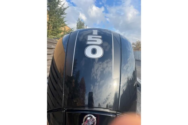 Slide: The Image of 2017 Tracker Pro Team 195 TXW boat engine with "150" marking, reflecting sky and trees. - 4