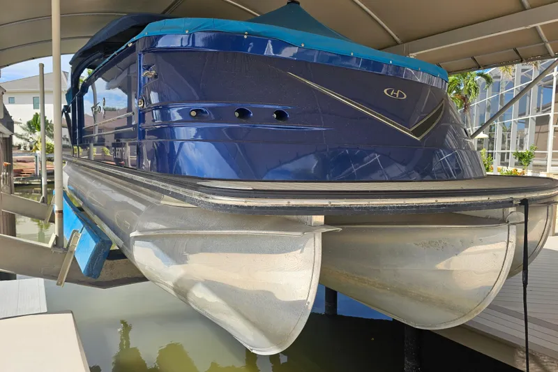 Slide: The Image of 2018 Harris V270 boat with blue exterior and canopy under a shelter. - 11