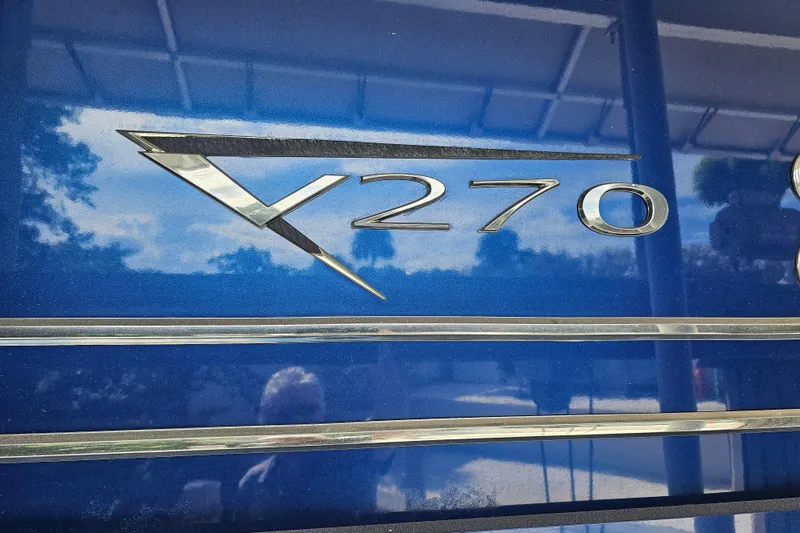 Slide: The Image of 2018 Harris V270 pontoon boat docked under canopy, surrounded by palm trees. - 16