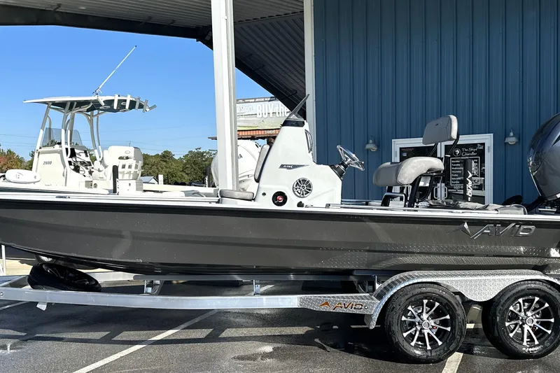 Slide: The Image of 2026 Avid 21 FSX boat on trailer, parked outside a blue building. - 2