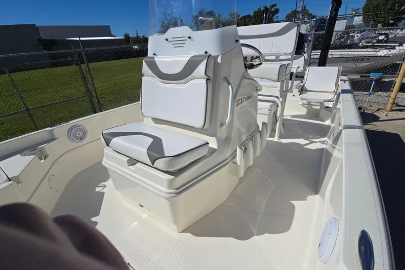 Slide: The Image of 2023 Skeeter SX230 boat interior with white seating and console, parked outdoors. - 21