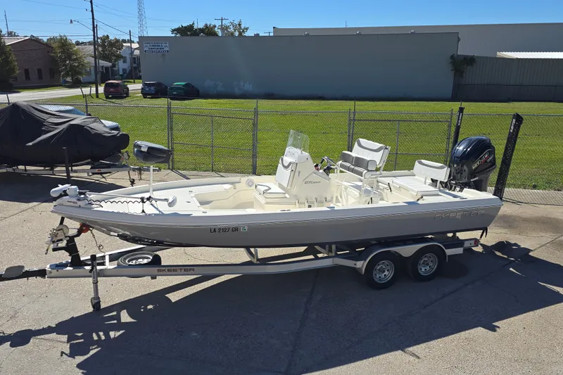 Slide: The Image of 2023 Skeeter SX230 boat on trailer, parked outdoors in a sunny setting. - 7