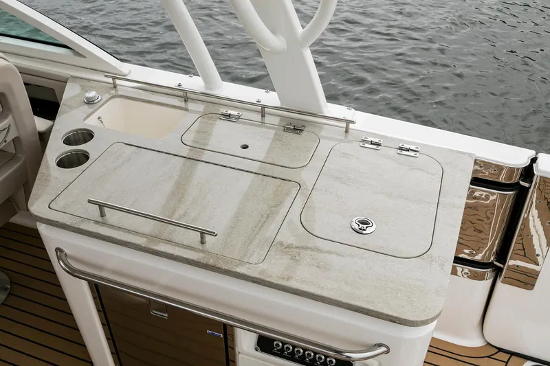 Slide: The Image of Manufacturer Provided Image: Boston Whaler 320 Vantage 2021 boat kitchen with sink and storage by the water. - 15