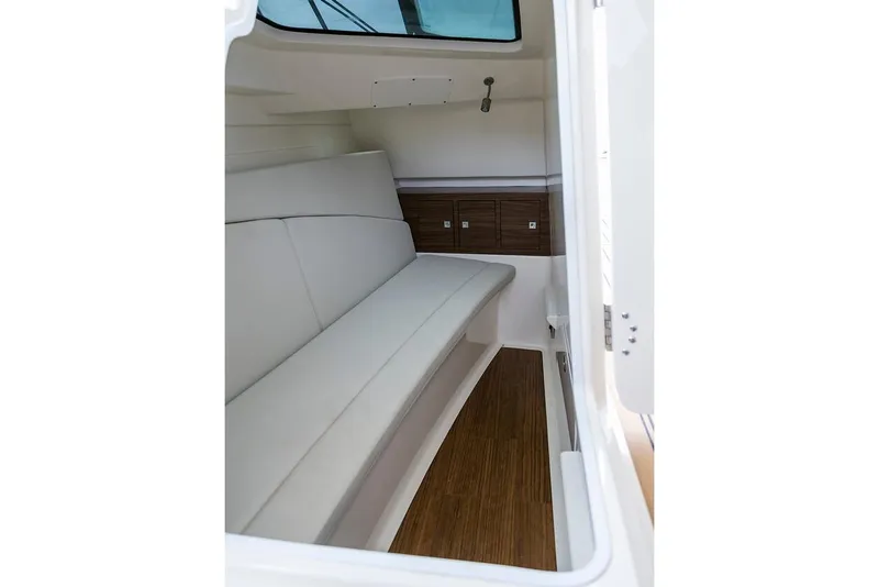 Slide: The Image of Manufacturer Provided Image: 2021 Boston Whaler 320 Vantage cabin interior with white seating and wooden flooring. - 20