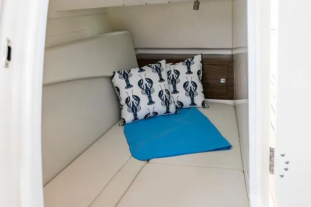 Slide: The Image of Manufacturer Provided Image: 2021 Boston Whaler 320 Vantage cabin with lobster-themed pillows and blue blanket. - 22