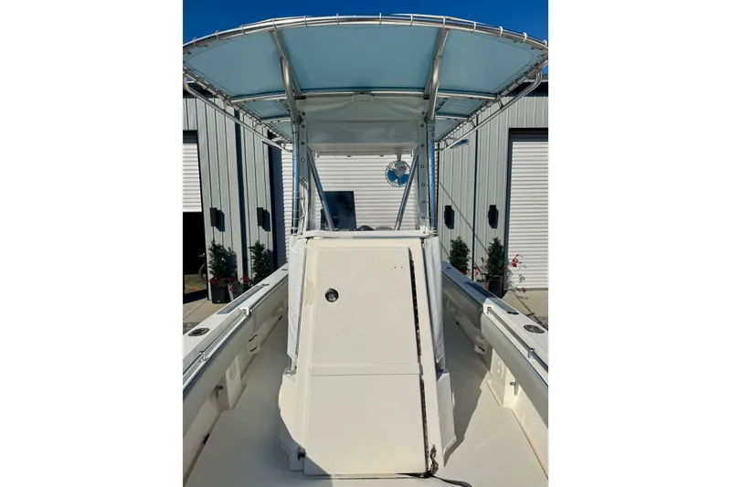 Slide: The Image of 2013 Contender 25 Tournament boat with T-top, docked near industrial buildings. - 11