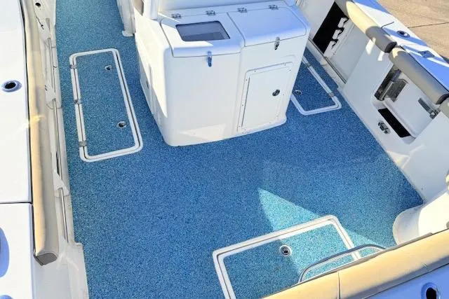 Slide: The Image of 2021 Tidewater 292 CC Adventure boat deck with blue flooring and storage compartments. - 5