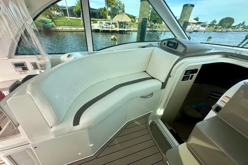 Slide: The Image of Interior of 2011 Cruisers Yachts 420 Sports Coupe with white seating and waterfront view. - 13