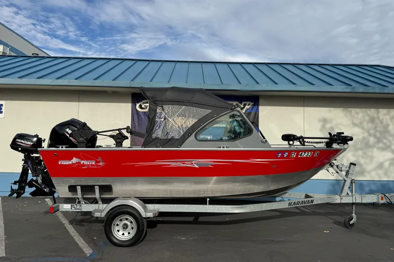 The Image of 2018 Fish Rite 16.5 Stalker boat on trailer, red and silver design, parked outdoors. - 1