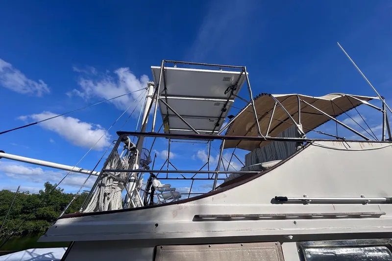 Slide: The Image of 1977 Marine Trader 40 Double Cabin yacht under clear blue sky, featuring upper deck and canopy. - 10
