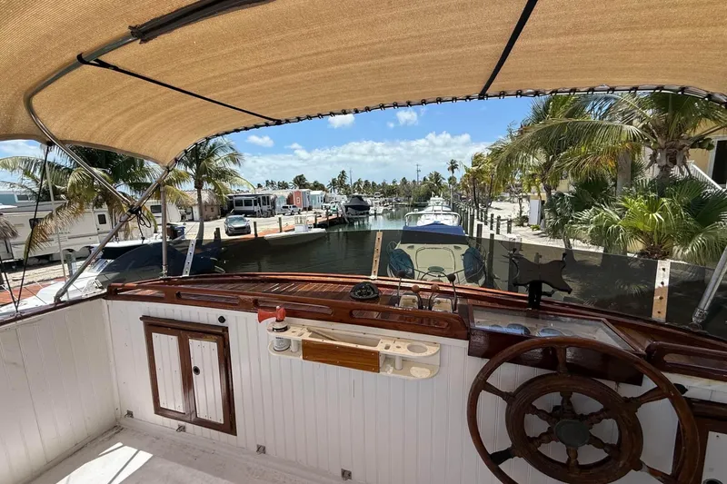 Slide: The Image of 1977 Marine Trader 40 Double Cabin yacht helm with canal view, palm trees, and sunny sky. - 11