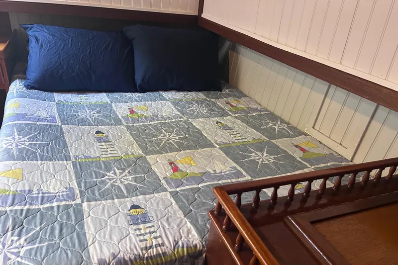 Slide: The Image of 1977 Marine Trader 40 Double Cabin interior with nautical-themed bedding and wooden accents. - 19