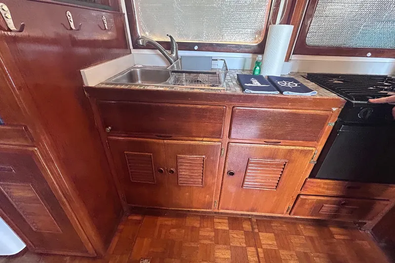 Slide: The Image of 1977 Marine Trader 40 Double Cabin kitchen with wooden cabinets and stainless steel sink. - 32