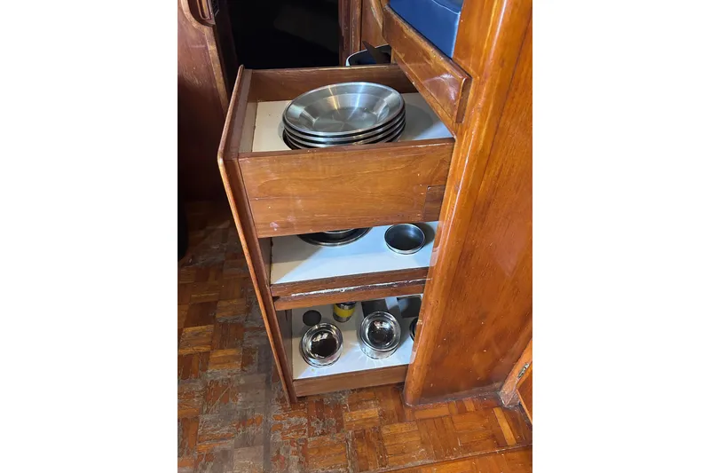 Slide: The Image of Wooden cabinet with metal dishes in a 1977 Marine Trader 40 Double Cabin boat. - 34