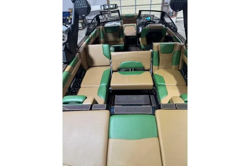 Slide: The Image of 2022 Malibu M240 boat interior with green and tan seating, modern dashboard, and spacious layout. - 7