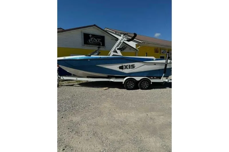 The Image of 2024 Axis T235 boat on trailer, parked outside a building on gravel. - 1