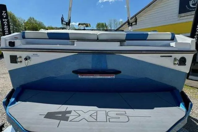Slide: The Image of 2024 Axis T235 boat rear view with blue and white seating, docked outdoors. - 5