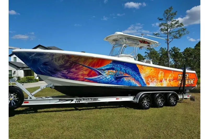 The Image of 2013 Sailfish 320 CC boat with vibrant marlin artwork on trailer. - 1