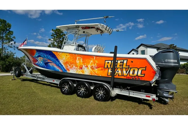 Slide: The Image of 2013 Sailfish 320 CC boat with vibrant graphics and Yamaha engine on a trailer. - 4