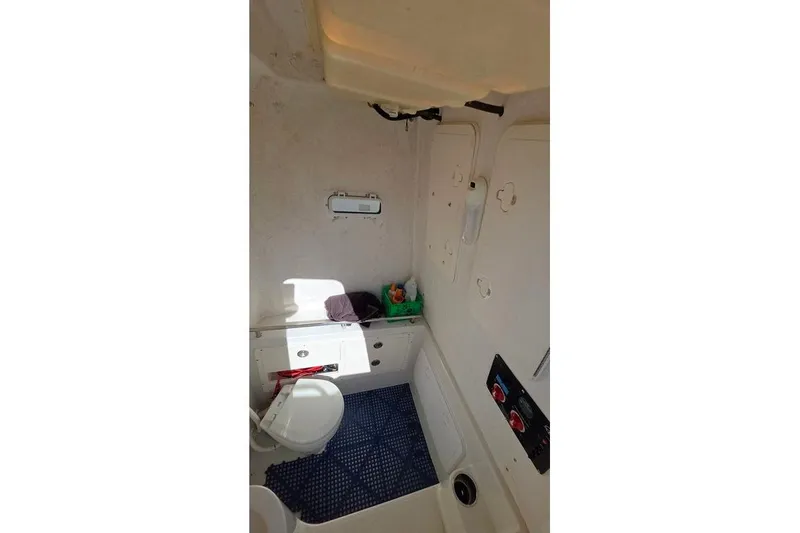 Slide: The Image of Interior of 2013 Sailfish 320 CC boat, featuring a compact bathroom with toilet and storage. - 44