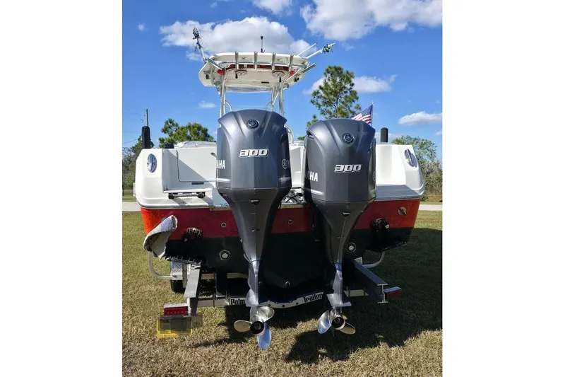 Slide: The Image of 2013 Sailfish 320 CC boat with dual Yamaha 300 engines, parked on grass. - 5