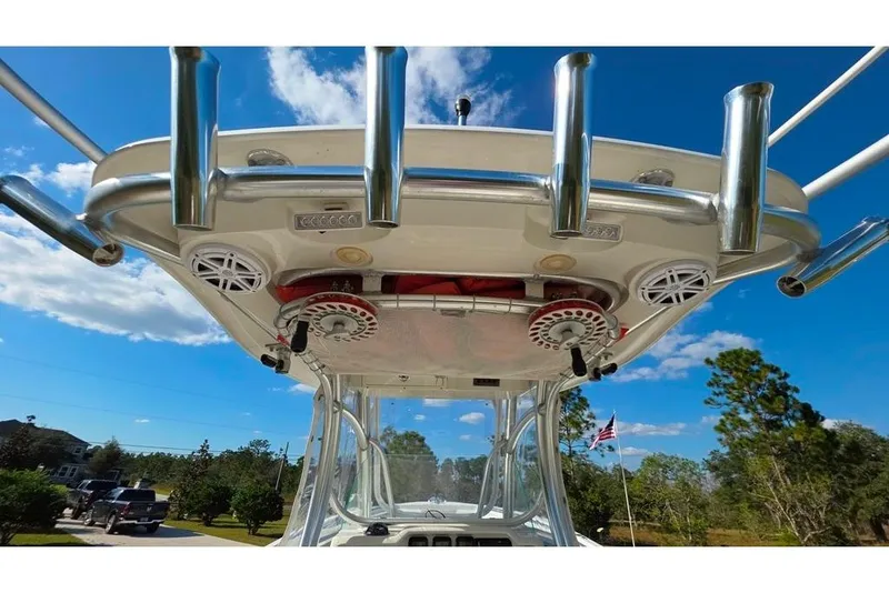 Slide: The Image of 2013 Sailfish 320 CC boat with rod holders and speakers under a clear blue sky. - 56