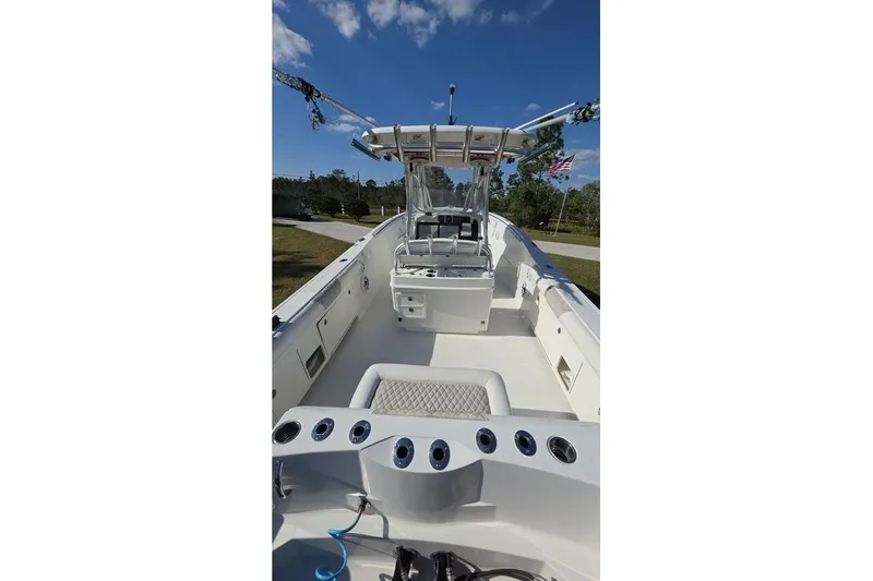 Slide: The Image of 2013 Sailfish 320 CC boat interior with fishing rod holders and seating under a clear sky. - 68