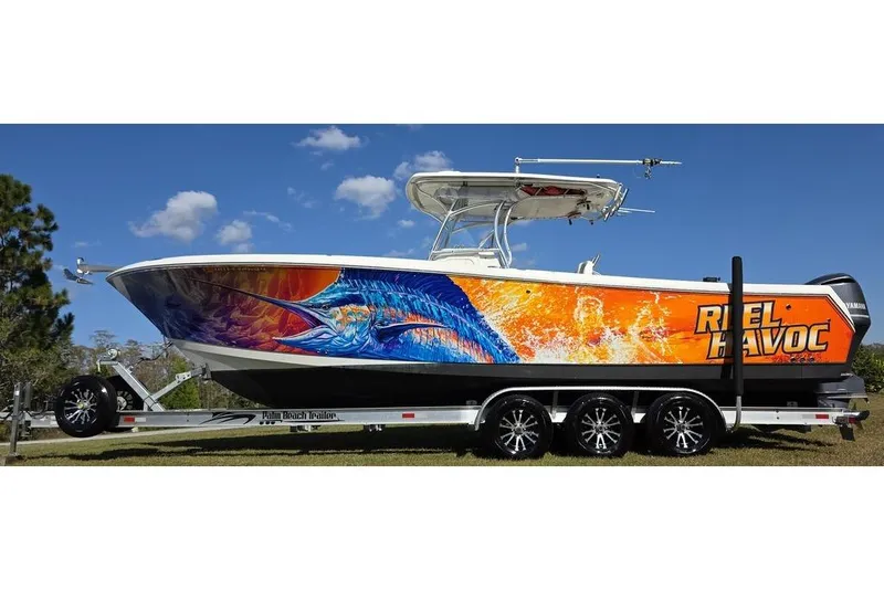 Slide: The Image of 2013 Sailfish 320 CC boat with vibrant marlin artwork on trailer under blue sky. - 8