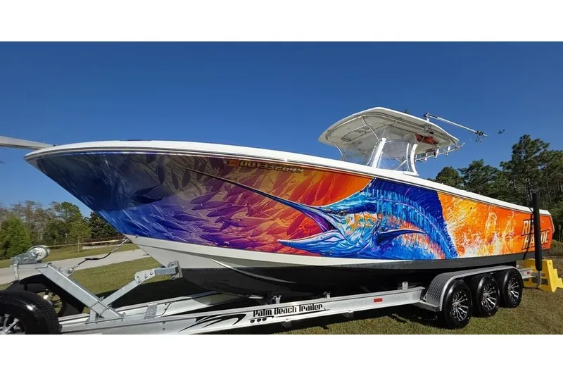 Slide: The Image of 2013 Sailfish 320 CC boat with vibrant marlin artwork on trailer. - 83