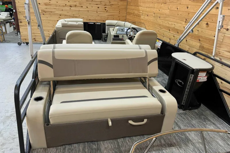 Slide: The Image of 2024 Crest Classic LX 220 SLSC pontoon boat interior with beige seating and wood paneling. - 10