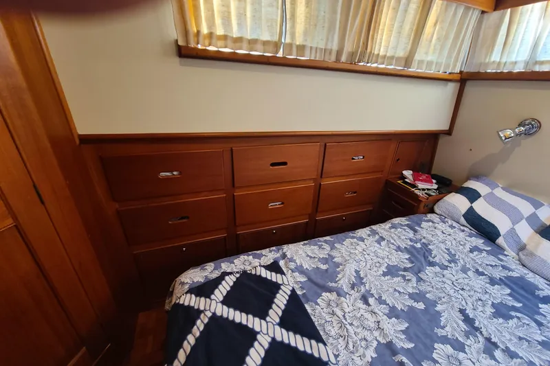 Slide: The Image of Cozy bedroom interior of 2000 Grand Banks 46 Classic yacht with wooden drawers and floral bedding. - 55