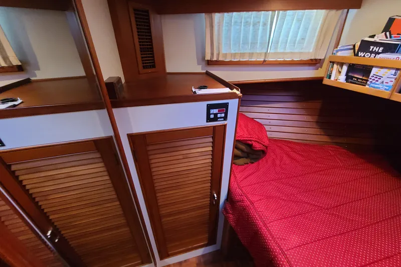 Slide: The Image of Cozy cabin interior of 2000 Grand Banks 46 Classic yacht with red bedding and wooden accents. - 67