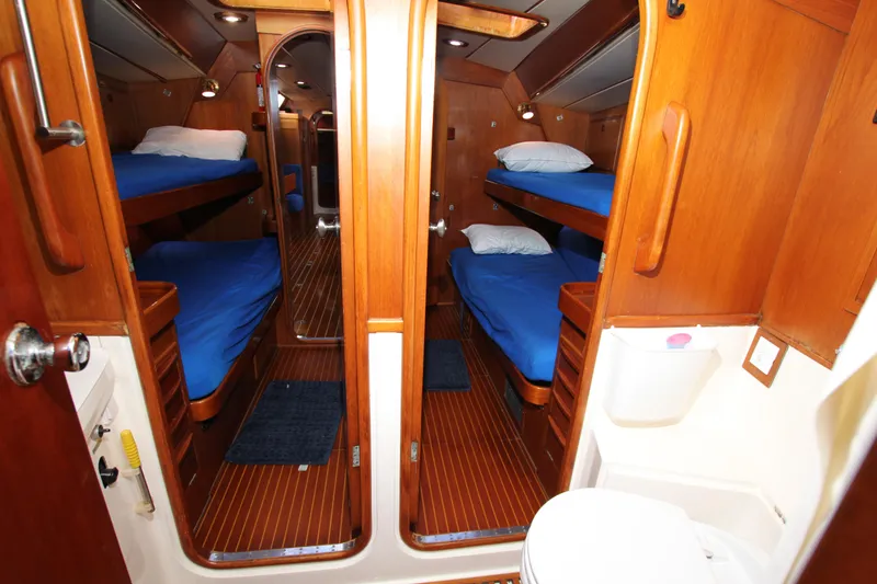 Slide: The Image of Interior of 1989 Nautor Swan 53 yacht with wooden bunk beds and blue bedding. - 25