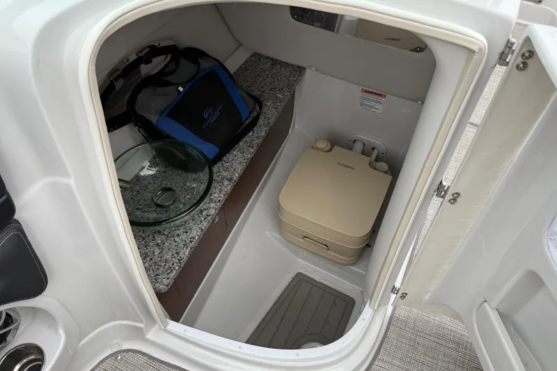 Slide: The Image of 2022 Crownline 255 SS boat interior with compact bathroom and storage area. - 9
