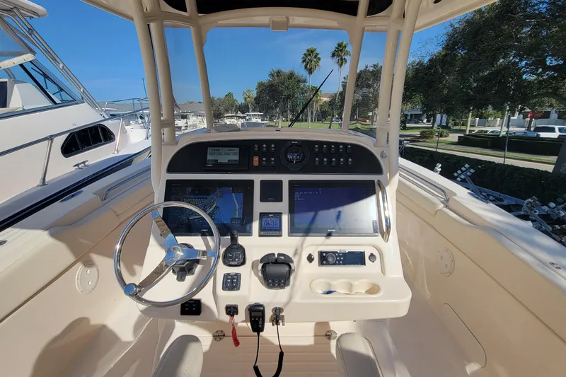 Slide: The Image of 2019 Grady-White Canyon 306 boat dashboard with steering wheel and navigation controls. - 14