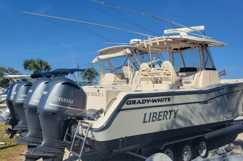 Slide: The Image of 2019 Grady-White Canyon 306 boat with Yamaha engines, named "Liberty," docked outdoors. - 2