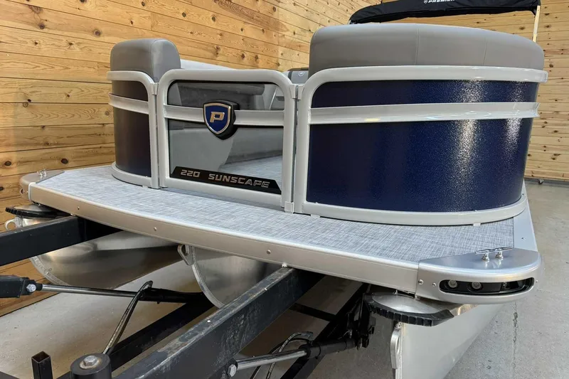 Slide: The Image of 2025 Premier Sunscape 220 RF XLC pontoon boat with sleek design in a wooden setting. - 5