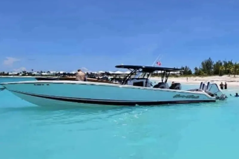 Slide: The Image of 2025 Nor-Tech 390 Sport Center Console boat in turquoise waters near a sandy beach. - 22