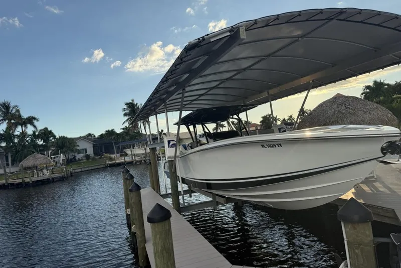 Slide: The Image of 2025 Nor-Tech 390 Sport Center Console boat docked under a canopy on a sunny day. - 8
