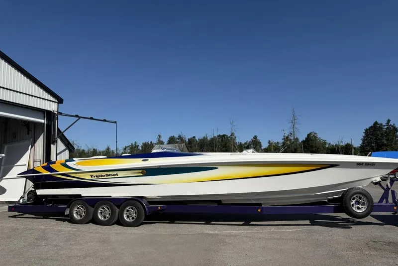 The Image of 1999 Hustler 388 SLINGSHOT powerboat on trailer, vibrant yellow and blue design. - 0