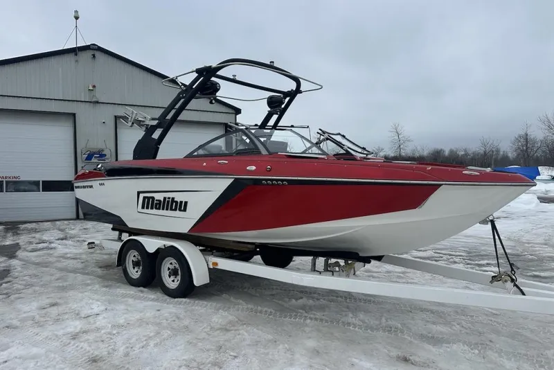 The Image of 2019 Malibu Wakesetter 23 LSV boat on trailer, parked outside a garage in snowy conditions. - 1