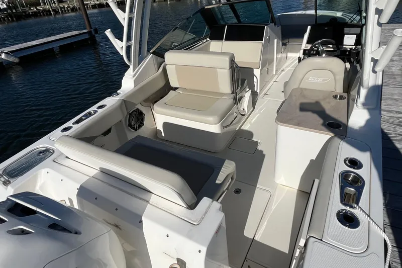 Slide: The Image of 2021 Boston Whaler 240 Vantage boat interior with seating and console, docked by the water. - 14