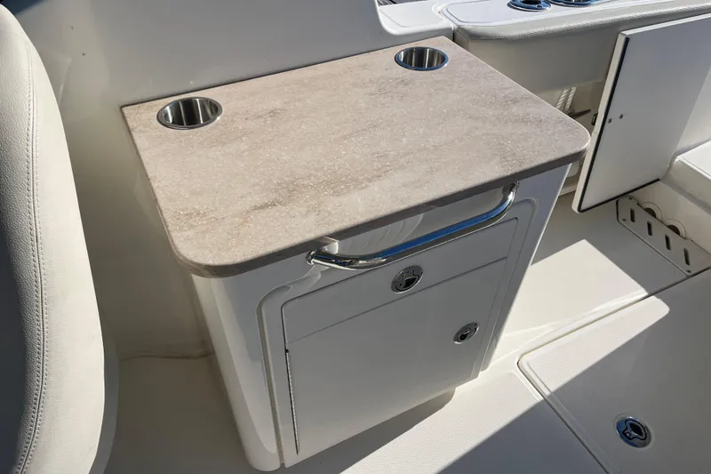 Slide: The Image of 2021 Boston Whaler 240 Vantage boat interior with cup holders and storage compartment. - 21